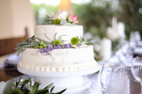 Close-up of a tiered wedding cake with buttercream icing and floral decorations on a cakestand at a wedding reception