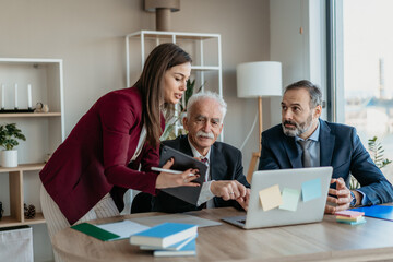 Multi-Generational Business Team Explaining Work to Senior Executive in Modern Office – Family...