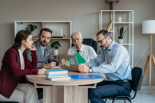 Multi-Generational Business Team Showing Work to Senior Executive in Modern Office &ndash; Mixed Generations