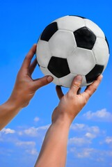 soccer ball in hand on a blue sky