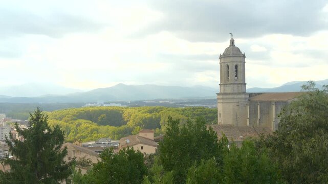 Peaceful View of Girona with Cathedral Tower and Distant Mountains Under Soft Cloudy Light in Catalonia