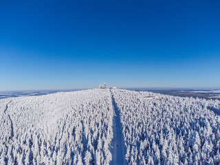 Winter panorama – Aerial view of a snow-covered mountain and mountain station peak under blue sky - Fichtelberg/Erzgebirge