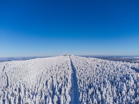 Winter panorama – Aerial view of a snow-covered mountain and mountain station peak under blue sky - Fichtelberg/Erzgebirge - Powered by Adobe