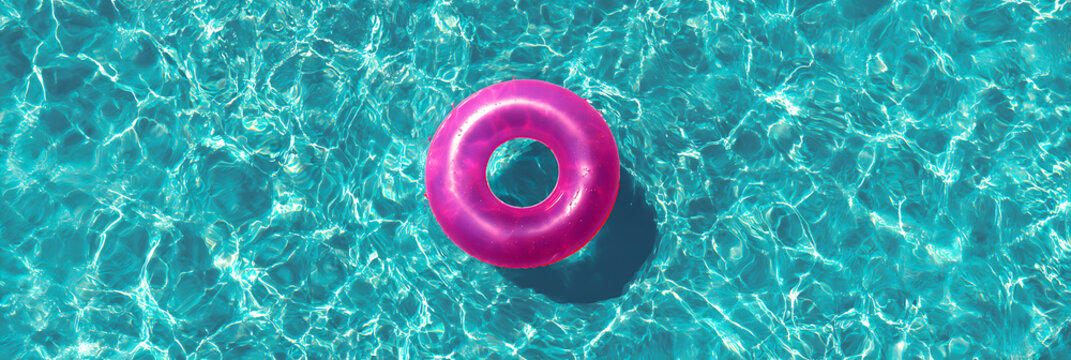 Vibrant pink swim ring floating on crystal clear turquoise pool water with shimmering sun reflections, ideal for summer vacation and travel banner.