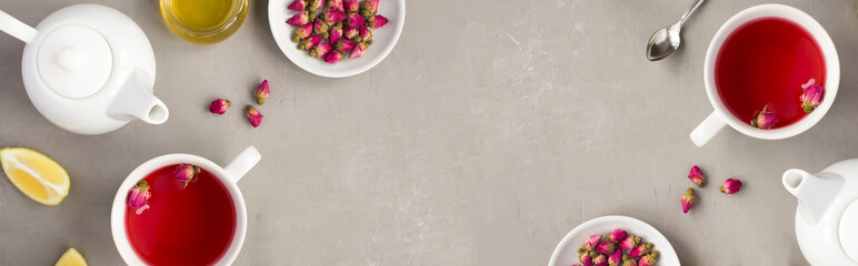 Herbal tea with pink roses on the gray concrete background. Top view. Copy space.
