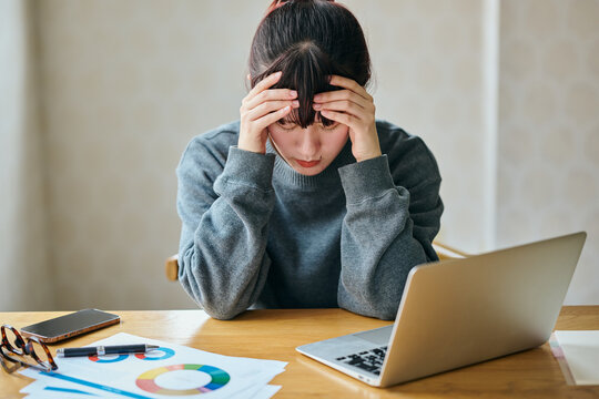 Stressed Businesswoman Suffering from Headache While Working on Laptop at Desk