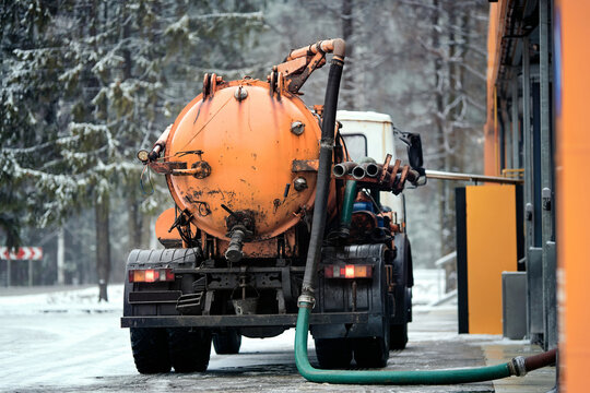 Vacuum truck pumping out liquid waste and silt from self service car wash drainage system during winter to ensure proper filtration and wastewater disposal services, cleaning of car wash facility