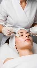 Naklejka premium Woman getting a facial mask applied by a cosmetologist. Beauty treatment at a spa. Skincare and aesthetic cosmetology concept.