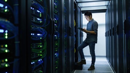 A man stands in a server room, holding a tablet and looking at the equipment. It conveys themes of technology, data management, and modern infrastructure.