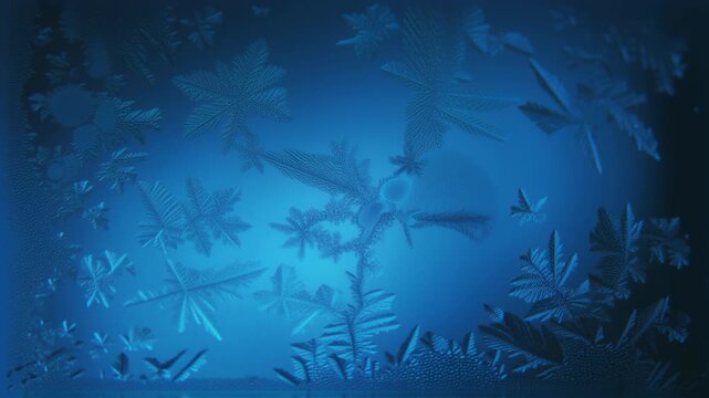 Frost patterns forming and growing on a blue glass surface. Abstract winter wonderland for seasonal background.