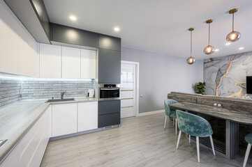 modern kitchen-dining area with white and grey cabinetry, grey brick-style backsplash, light wood...