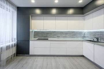 sleek grey-and-white kitchen with minimalist cabinetry, grey brick-style backsplash, light wood...