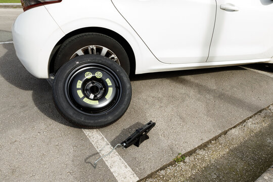 a temporary spare wheel resting on the car, ready to be changed