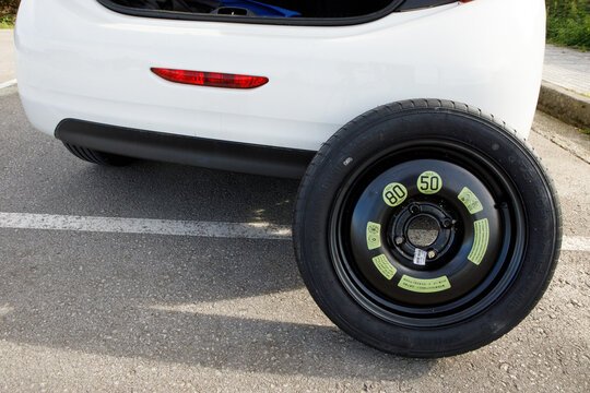 a temporary spare wheel resting on the car, ready to be changed
