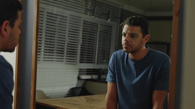 Serious man Staring at Himself in the Mirror at Night
