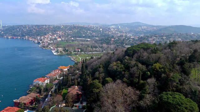 Aerial drone footage of the Kandilli and Vanikoy coastline along the Bosphorus in Istanbul, showing hillside residences, red-roof homes, coastal roads and the wide blue strait stretching into the dist