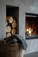 A cozy fireplace creates a warm and inviting ambiance, with logs, a basket, and a soft blanket.