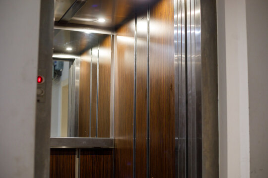 Empty modern elevator interior with mirror, stainless steel and wood panels, clean urban architecture, minimal design background, copy space, vertical composition