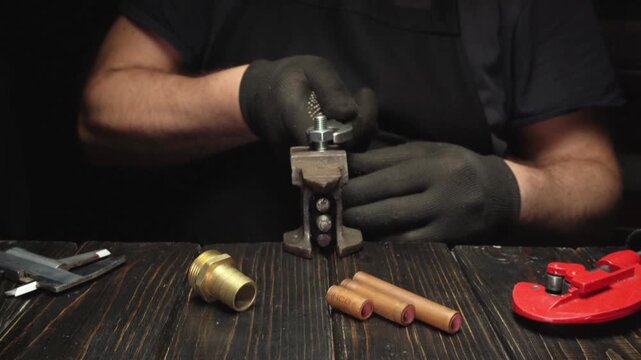 Working with tools and materials for plumbing on a wooden workbench in a workshop during daytime
