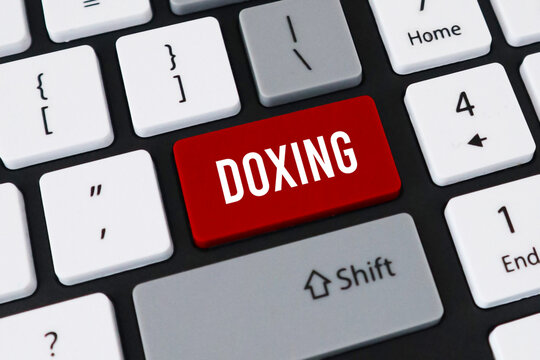 Red doxing button on computer keyboard. Concept of private data exposure, online harassment and cyber security.