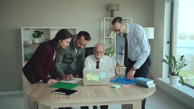 Multi-Generational Business Team Showing Work to Senior Executive in Modern Office &ndash; Mixed Generations
