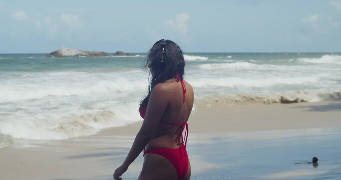 Under the radiant warmth of the Caribbean sky, a Latina girl in a bold red bikini finds her escape along the pristine, palm-fringed sands of Yarra Beach.