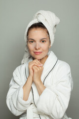 Cheerful young woman with moisturizing, rejuvenating white fabric sheet mask from her face smiling at camera on white background
