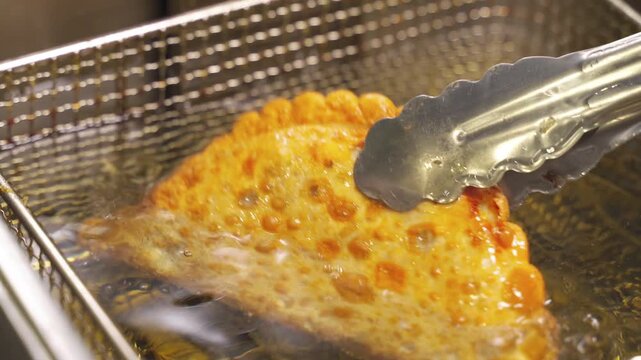 Watch as golden chebureki sizzle in hot vegetable oil, creating a crispy texture. The mouthwatering aroma fills the kitchen, inviting you to indulge in this delightful dish.