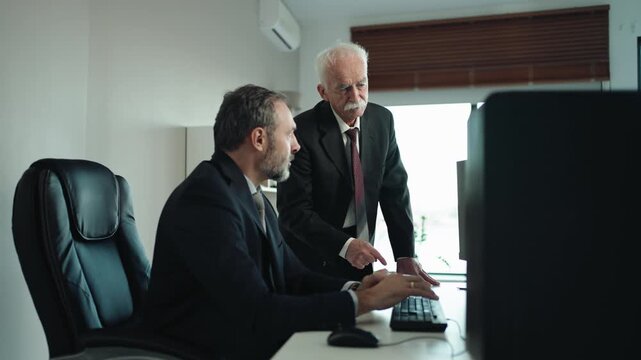 Middle Aged Businessman Training Senior Colleague on Computer Technology