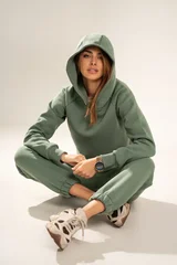 Confident young woman wearing a mint athleisure set with sweatshirt and sweatpants, posing in a minimal studio on a light background. Modern casual fashion, comfort wear, sporty lifestyle © neonshot