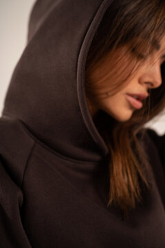 Portrait of beautiful, natural woman in brown hoodie. Girl with long dark hair.