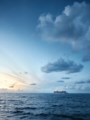 Obraz premium Minimal seascape with ship on the horizon under dramatic clouds at dusk, wide sky copy space for travel, business and freedom concept background