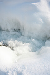 Close-up of icy river surface with frozen textures, cracks and flowing cold water, abstract winter nature background.