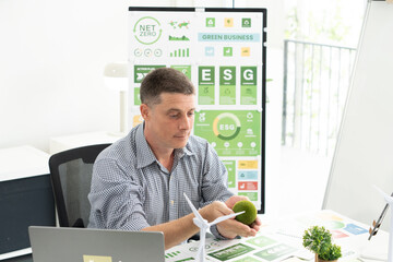 A diverse business team analyzing environmental charts and graphs in a collaborative meeting to create sustainable strategies in a modern office.