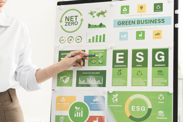 A diverse business team analyzing environmental charts and graphs in a collaborative meeting to create sustainable strategies in a modern office.