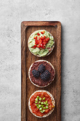 Puffed rice cakes with toppings on a wooden board. Top view