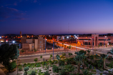Cityscape at dusk with beautifully lit streets and silhouetted buildings under a purple sky. Ouarzazate, Morocco