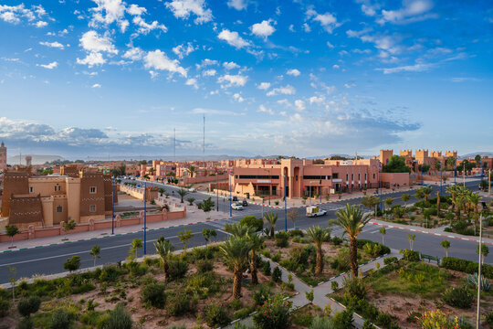 Aerial view of a cityscape with terracotta buildings under a blue sky and scattered clouds. Ouarzazate, Morocco