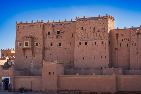 Ancient clay building with intricate designs under a vibrant blue sky. Ouarzazate, Morocco