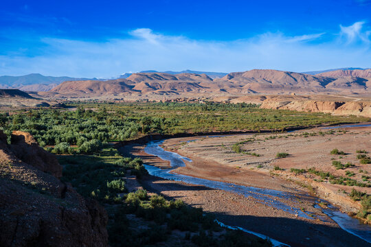 Vast desert landscape with a winding river and distant mountains under a clear blue sky. Ouarzazate, Morocco