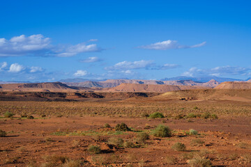 Vast desert landscape with distant mountains under a clear blue sky and scattered clouds. Ouarzazate, Morocco