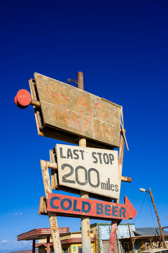 Rusty road sign for a tavern and cold beer under a clear blue sky in a desert area. Ouarzazate, Morocco