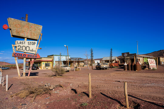Desert gas station with vintage signs, old cars, and clear blue sky on a sunny day. Ouarzazate, Morocco