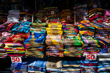 Colorful stacks of folded clothing arranged neatly with price signs in a vibrant marketplace. Rabat, Morocco