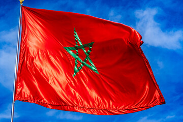 Bright red Moroccan flag with green star on a clear blue sky background. Rabat, Morocco