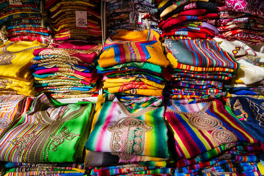 A colorful display of folded, patterned textiles stacked in vibrant layers at a market stall. Rabat, Morocco