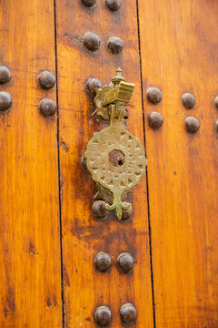 Ornate metallic door knocker on a vintage wooden door with decorative details. Rabat, Morocco