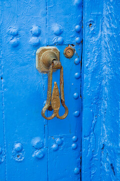 Bright blue wooden door with rustic metal knocker and visible textured details. Rabat, Morocco
