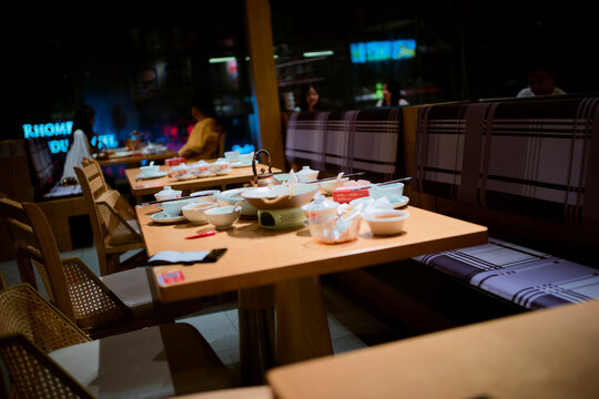 Empty restaurant tables with unfinished meals and dim lighting create a cozy atmosphere. Chengdu, Sichuan, China