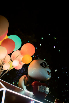 A playful panda figure with colorful balloons against a dark, starry backdrop. Chengdu, Sichuan, China